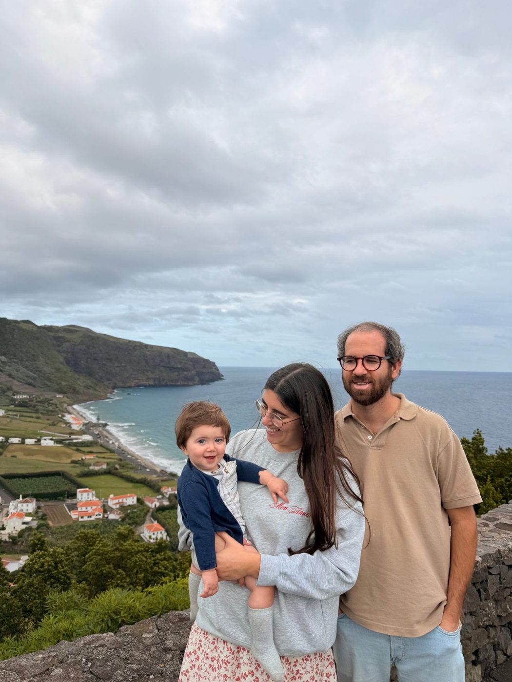 A Mariana com o Joaquim Maria ao colo e o marido, num miradouro sobre o mar